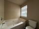 A soaking tub beneath a window is adjacent to the toilet in this bathroom at 5488 Wexford Pass, Atlanta, GA 30349