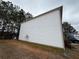 Side view of the home with white siding and a well-maintained lawn and surrounding trees at 5488 Wexford Pass, Atlanta, GA 30349