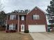 Charming two-story brick home featuring black shutters, a two-car garage, and well-maintained landscaping at 5488 Wexford Pass, Atlanta, GA 30349