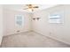 An empty bedroom boasts neutral carpet, two bright windows, a ceiling fan, and a simple shelf at 80 Brownsville Ext., Powder Springs, GA 30127