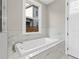 This soaking tub sits under a window with marble surrounding and bright light at 1360 Flora Dr, Conyers, GA 30094