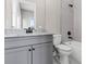 Bathroom featuring a gray vanity with a white countertop, toilet, tub with white tile, and a framed mirror at 1360 Flora Dr, Conyers, GA 30094