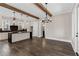 Open kitchen with wood floors, a large island with black countertops, white cabinets, wood beams, and modern lighting at 1360 Flora Dr, Conyers, GA 30094