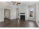 Open-concept living room with a ceiling fan, fireplace with white shiplap, wood floors, and three large windows at 1360 Flora Dr, Conyers, GA 30094