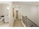 Well-lit hallway with wood floors, leading to a bathroom with a white vanity, and staircase featuring a black railing at 5047 Chesterfield Ln, Dunwoody, GA 30338