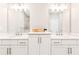 Bathroom featuring dual vanities with modern fixtures, white cabinetry, and a tiled shower in the mirror's reflection at 677 Brennan Dr, Decatur, GA 30033