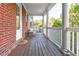 Inviting covered porch with brick wall, white columns, wooden floors, and seating area at 677 Brennan Dr, Decatur, GA 30033