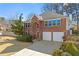 Brick home with an attached two-car garage, manicured bushes and lush trees at 3744 Misty Wood Nw Dr, Marietta, GA 30064