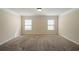 A carpeted bedroom with natural light from two windows, and neutral walls at 2592 Jacanar Sw Ln, Atlanta, GA 30331