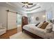 Spacious main bedroom featuring a tray ceiling, ceiling fan, hardwood floors, and a sliding barn door to the bathroom at 3979 Sentry Xing, Marietta, GA 30068