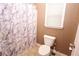 Small bathroom with tiled floors, toilet, combination tub and shower with curtain, and single window at 460 Chandler Bluff Ct, Grayson, GA 30017