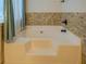 A tiled bathtub with mosaic tile trim and bronze fixtures at 477 Harvick Cir, Stockbridge, GA 30281