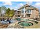 Stunning backyard featuring a large pool, hot tub, outdoor fireplace and a screened-in porch at 6980 Polo Fields Pkwy, Cumming, GA 30040