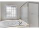 Bathroom featuring a jetted tub under a window and a glass shower at 1900 Sanborne Way, Dacula, GA 30019