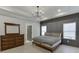 This main bedroom features a modern dresser, tray ceiling with modern chandelier, and large windows at 2905 Ivy Mill Drive Dr, Buford, GA 30519