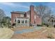 Landscaped backyard with stone patio, and beautiful red brick home under a clear blue sky at 370 Laurel Oak Dr, Suwanee, GA 30024