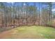 Expansive backyard with lush green grass, mature trees, and a charming fire pit area for outdoor enjoyment at 708 Players Ct, Woodstock, GA 30189