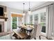 Well-lit dining area with a wooden table, bench seating, and large windows with backyard views at 708 Players Ct, Woodstock, GA 30189