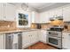 Cozy kitchen featuring stainless steel appliances, granite countertops, and white cabinets at 708 Players Ct, Woodstock, GA 30189