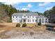 Elegant white home with a manicured lawn and a stone retaining wall in a peaceful wooded setting at 5245 Emmett Still Rd, Loganville, GA 30052