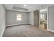 Bedroom with neutral carpet, tray ceiling, and a doorway that offers seamless flow to another living area at 1988 Boulderview Se Dr, Atlanta, GA 30316