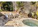Inviting backyard featuring a stone patio with Adirondack chairs and a relaxing hot tub surrounded by lush greenery at 2146 Wolbert Trl, Marietta, GA 30062
