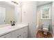 Clean bathroom featuring a single sink vanity, large mirror, and toilet at 372 Rustic Ridge Cir, Lawrenceville, GA 30043