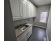 Well-lit laundry room with sink, storage cabinets, and gray flooring at 7910 Tintern Trce, Duluth, GA 30097