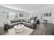 Bright living room with hardwood floors, a large sectional sofa, and modern decor, with a view to an adjacent office space at 8540 Hope Mews Ct, Atlanta, GA 30350