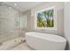 Modern bathroom featuring large shower with glass door and a standalone white soaking tub under a window at 727 Crest Line W Trl, Powder Springs, GA 30127