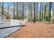 Image showcasing a spacious backyard with a wooden deck, white picnic table, and storage shed among the trees at 806 Longfellow Ct, Stone Mountain, GA 30088