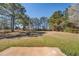 View of the grassy backyard surrounded by mature trees on a sunny day at 105 Bentley Place Way, Covington, GA 30016