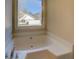 Window with a view from a bathroom features a large soaker tub with jets at 105 Bentley Place Way, Covington, GA 30016