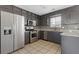 Well-lit kitchen featuring stainless steel appliances, granite countertops, tile backsplash, and gray cabinetry at 1116 Oak Hollow Ln, Hampton, GA 30228