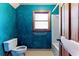 This blue-walled bathroom features a toilet, bathtub and small framed window at 1505 Ozora Rd, Loganville, GA 30052