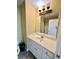 Bathroom vanity featuring white cabinets, neutral countertops, and a framed mirror with a decorative light fixture at 3585 Shepherds Ln, Loganville, GA 30052