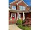 Close-up of a brick home's entryway with a red door, rocking chairs, and well-kept landscaping at 3585 Shepherds Ln, Loganville, GA 30052