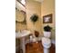 Small powder room with pedestal sink, decorative mirror, and hardwood floors at 3585 Shepherds Ln, Loganville, GA 30052