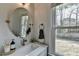 Powder room with round mirror, designer faucet, and a view to a fenced in backyard at 10815 Donamere Dr, Johns Creek, GA 30022
