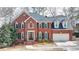 Traditional two-story brick home with manicured front lawn, black shutters, and attached two-car garage at 10815 Donamere Dr, Johns Creek, GA 30022