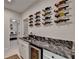 Wine bar with black marble counters, wine fridge, and artistic wine bottle display on the wall at 10815 Donamere Dr, Johns Creek, GA 30022