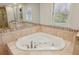 A bright bathroom displays a relaxing jetted soaking tub with tile surround and a large window at 2805 Roxburgh Dr, Roswell, GA 30076