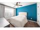Cozy bedroom with a large window, tufted headboard, ceiling fan, and stylish blue accent wall at 1605 Camden Cove Dr, Cumming, GA 30040
