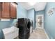 Well-lit laundry room featuring modern washer/dryer, utility sink, cabinet and tile flooring at 1605 Camden Cove Dr, Cumming, GA 30040