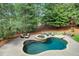 A backyard oasis showcases a sparkling pool and spa, surrounded by lush landscaping, lounge chairs, and mature trees at 4992 Price Dr, Suwanee, GA 30024
