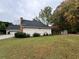 Side exterior view of home featuring a two-car garage, brick chimney, and well-maintained landscaping at 2020 Wynfield Point Dr, Buford, GA 30519