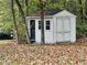 Charming backyard shed with a black door and white trim, nestled among trees and fallen leaves at 2020 Wynfield Point Dr, Buford, GA 30519