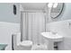 This bathroom features a toilet, sink, and shower with black and white striped curtain and white tile walls at 1309 Arnold Ne Ave, Atlanta, GA 30324