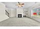 Bright living room with fireplace, modern ceiling fan, plush carpet, and natural light from large windows at 1566 Wilson Manor Cir, Lawrenceville, GA 30045
