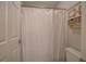 Simple bathroom with a white shower curtain, toilet, and decorative shelving unit at 3534 Brandywine Nw Rd, Kennesaw, GA 30144